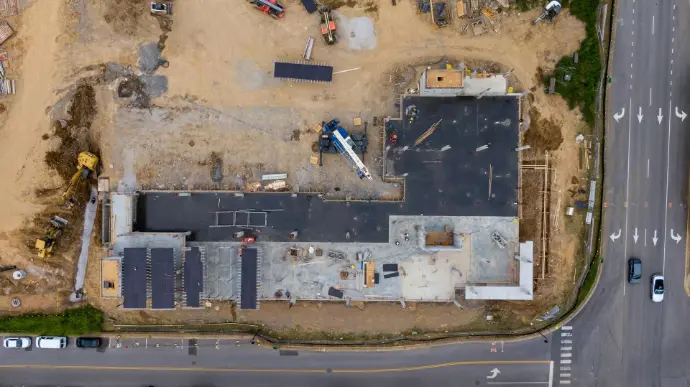 Vista aérea cenital de una obra de construcción en Málaga, mostrando los cimientos, estructuras en progreso, maquinaria pesada y materiales de construcción, así como la carretera adyacente. Esta imagen es ideal para empresas de construcción y promotoras inmobiliarias en Málaga que requieran un seguimiento detallado de sus proyectos. Los drones permiten realizar inspecciones de obra, controlar el avance de los trabajos, documentar cada fase y generar informes precisos, optimizando la gestión de grandes construcciones y desarrollos inmobiliarios en la provincia.