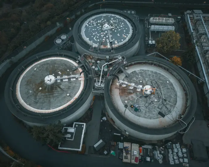 Vista aérea cenital de una instalación industrial en Málaga, posiblemente una planta de tratamiento de aguas residuales o una fábrica con grandes tanques de almacenamiento y maquinaria compleja, rodeada por sus accesos y perímetros. La imagen es ideal para empresas industriales y de servicios en Málaga que requieran inspecciones de infraestructuras críticas, seguimiento de operaciones o documentación visual de sus instalaciones. Los drones permiten realizar un mantenimiento predictivo, inspeccionar áreas de difícil acceso y garantizar la seguridad de grandes complejos industriales y naves en la provincia de Málaga.