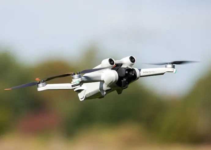 Primer plano de un dron DJI Mini 3 Pro en vuelo, destacando su diseño compacto, sus cámaras y sensores, con un fondo desenfocado que sugiere un entorno abierto. Aunque la imagen no muestra un paisaje de Málaga, es crucial para tu negocio de drones en la región. Esta foto es perfecta para presentar el equipo de alta tecnología que utilizas para tus servicios de fotografía y vídeo aéreo en Málaga, como el DJI Mini 3 Pro o el DJI Mini 4 Pro, enfatizando la calidad y precisión de tus grabaciones y la capacidad para operar drones de última generación en la provincia de Málaga.