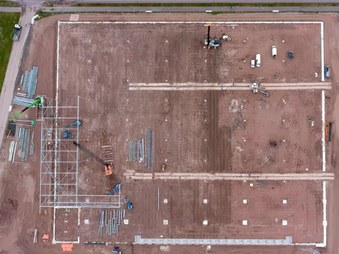 Vista aérea cenital de un vasto terreno en Málaga, preparado para la construcción, con el movimiento de tierras ya realizado y los cimientos marcados para una gran estructura, posiblemente una nave industrial o un complejo logístico. Se observan materiales de construcción, maquinaria y algunas grúas, delineando el progreso inicial del proyecto. Esta imagen es ideal para empresas de construcción, promotoras o inversores en Málaga que necesiten documentar y supervisar grandes movimientos de tierra, la preparación del terreno y el inicio de la fase de cimentación, garantizando un control preciso y eficiente de los proyectos desde una perspectiva aérea.